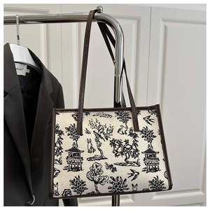 Dettaglio della borsa tote in tela con stampa vintage e manici in pelle marrone
