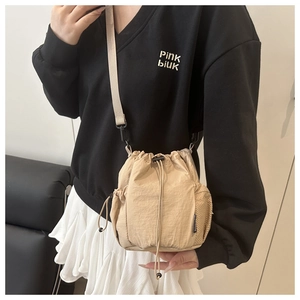 Detail of light beige nylon drawstring bucket bag with pleated texture and side mesh pocket