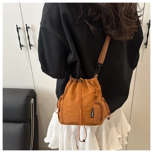 Detail of brown nylon drawstring bucket bag with mesh pocket and black cord lock