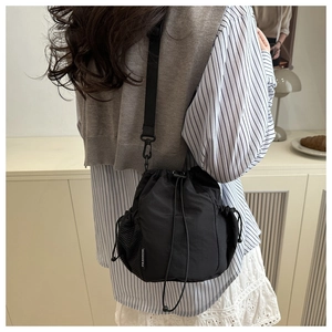 Detail of a black nylon drawstring bucket bag showing side mesh pocket and fashion label
