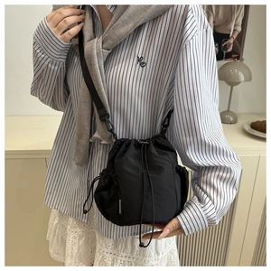 Detail of black nylon drawstring bucket bag with mesh side pockets and fashion label