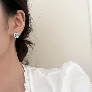 Close-up of elegant silver round stud earrings with green opal and zircon accents