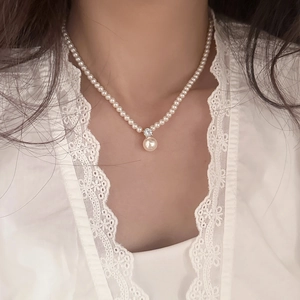 Elegant single-strand pearl necklace featuring a brilliant zircon pendant on lace background