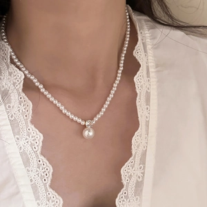 French vintage pearl necklace with a central diamond-set pendant on a model neckline