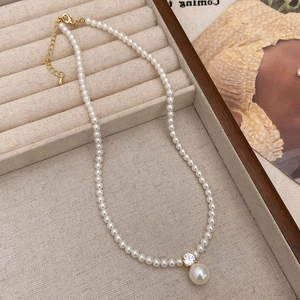 Detail of elegant pearl necklace with zircon pendant on cream jewelry box
