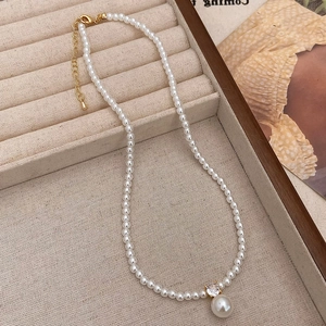 Detail of elegant pearl necklace with zircon pendant on a beige jewelry display tray