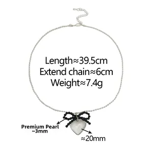 Detail of transparent heart pendant with black beaded bow on silver chain necklace