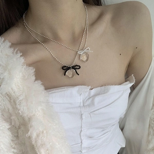 Close-up of double-layer necklace with transparent heart pendants and bow details