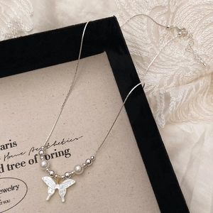 Detail of shell butterfly pendant necklace with pearls on lace and vintage canvas