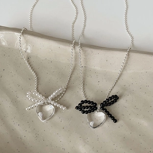 Transparent heart pendant necklace with beaded bow accent on silver ball chain