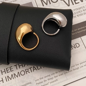 Minimalist 18K gold and silver teardrop rings on black leather with mirror polished finish