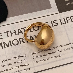 Macro view of 18K gold liquid drop ring with high-polish finish on vintage paper
