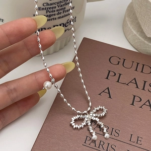Silver bow pendant pearl necklace featuring a metallic bead chain in a retro chic style