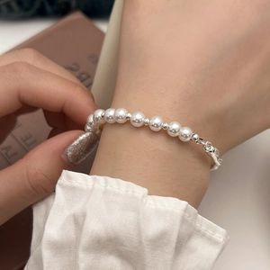 Detail of white pearl bracelet with silver metallic spacers on a rustic book background