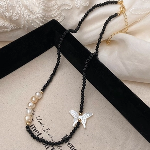 Détail d'un collier en spinelle noir avec pendentif papillon et perles d'eau douce