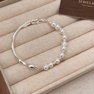 Detailed shot of silver textured metal and pearl bracelet in a velvet gift box