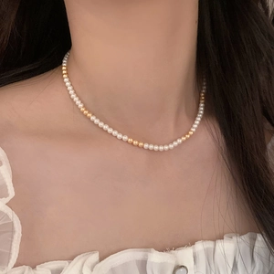 Gros plan d'un collier de perles blanches et de perles dorées sur le cou d'un mannequin