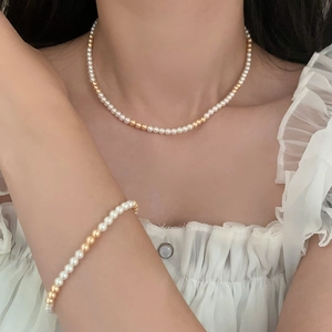 Ensemble de perles et billes dorées vintage porté par un mannequin en chemisier blanc