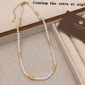 Détail du collier de perles blanches et dorées avec fermoir mousqueton réglable