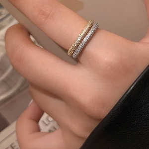 Close-up of stacked gold and silver micro-pave zircon rings on a model's finger