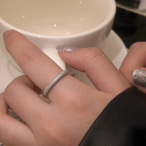 Close-up of sparkling full-zircon silver ring worn while holding a white ceramic coffee cup