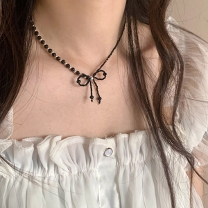 Detailed view of a black beaded choker with a central bow design and silver accents