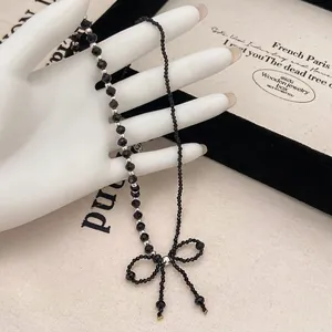 Elegant black beaded choker necklace featuring a delicate bow pendant for women