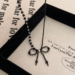 Elegant black beaded choker featuring a handcrafted crystal bow pendant and silver accents