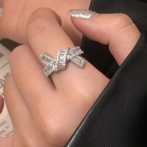 Detail of silver bow knot ring with zircon inlay shown on hand with newspaper background