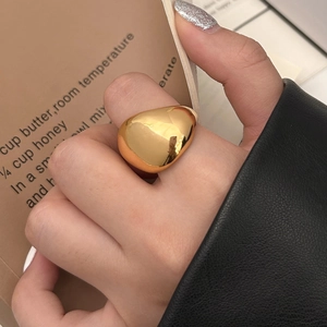 Close-up of polished gold-plated irregular teardrop ring worn on finger with minimal design