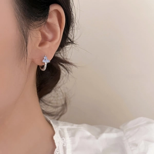 Silver geometric hoop earring with blue floral gems and diamonds on female model