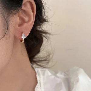 Elegant gold flower hoop earrings with blue stones and crystals worn by a woman