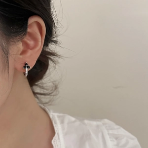 Detail view of a silver three-petal flower earring with black stones and white micro-zirconia