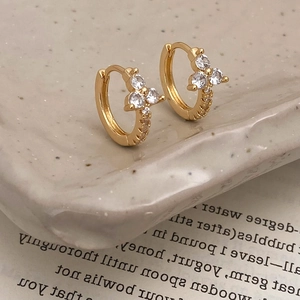 Detail of 18K gold huggie earrings featuring micro-pave zircon flower design