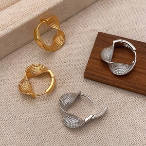 Créoles torsadées texturées or et argent sur fond de tissu minimaliste élégant et chic