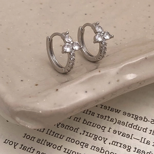 Detailed view of silver hoop earrings with zircon petal design on a vintage book