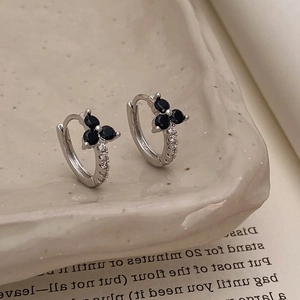 Macro shot of silver clover hoop earrings with black stones and micro-pave white zircons