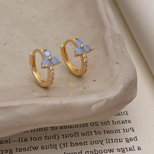 Macro shot of gold earrings with blue opal-like stones and white zircon accents