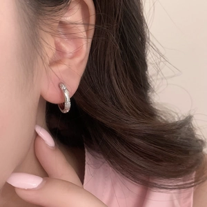Gros plan de boucles d'oreilles huggies argentées avec micro-pavage de zircons sur un modèle