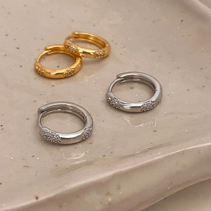 Élégantes créoles en or et argent avec zircons sur un plateau de présentation