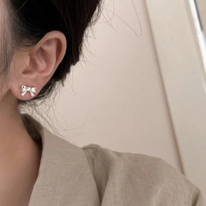 Minimalistische silberne Schleifenohrringe am Model mit zartem Metallic-Finish und Design