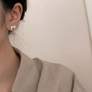 Nahaufnahme von minimalistischen silbernen Schleifen-Ohrsteckern mit edlem Metall-Finish