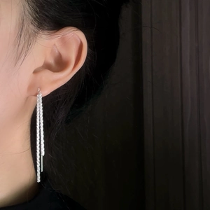 Macro detail of silver long tassel earrings with three delicate metallic chains