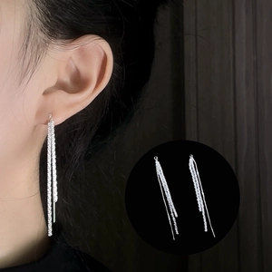 Close-up of sparkling silver tassel drop earrings on a model showing layered long chains
