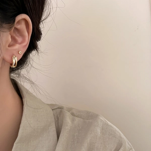 Gros plan de boucles d'oreilles doubles anneaux dorés avec pavé de zircons sur modèle