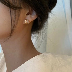 Close-up of elegant gold layered hoop earrings with sparkling rhinestones on a female ear