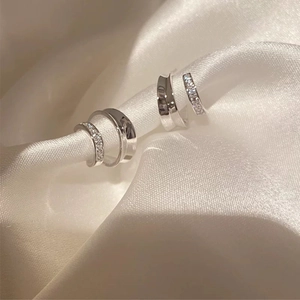 Macro view of silver hoop earrings featuring polished metal and pavé zircon settings