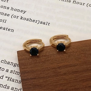Detailed view of gold hoop earrings featuring a classic four-prong set black zircon stone