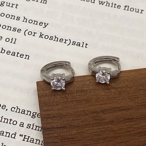 Close-up of silver-tone hoop earrings with round cubic zirconia in four-prong setting