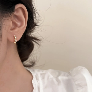 Elegante florale Zirkon-Ohrstecker in Gold-Optik, getragen von Model mit Spitzenkragen